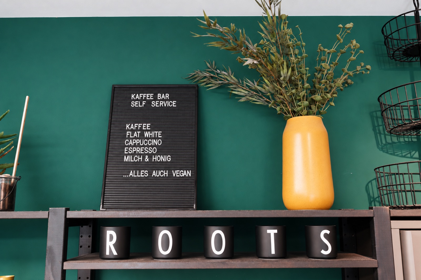 Kaffeebar mit ROOTS-Schriftzug und gelber Vase im Salon
