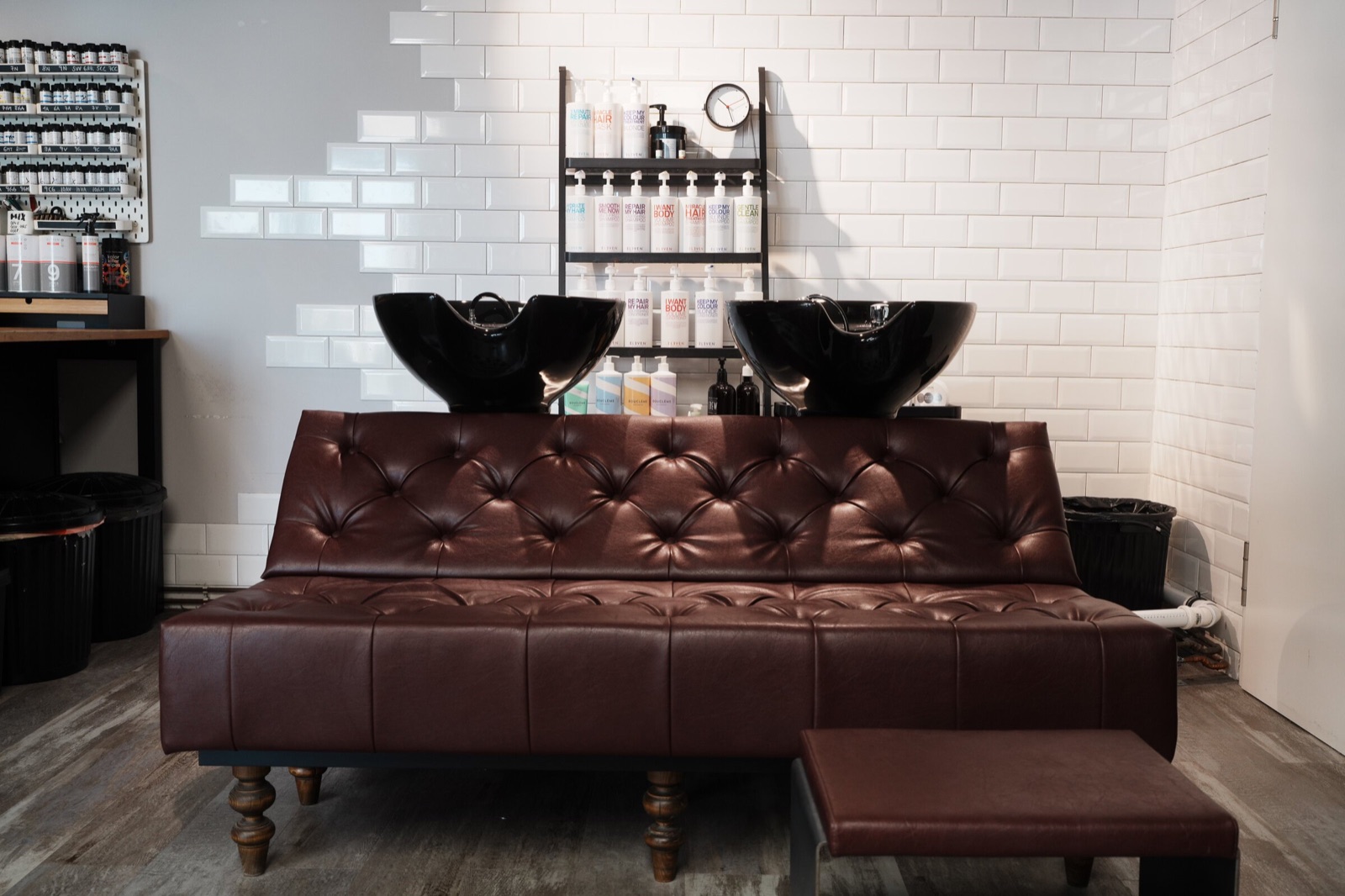 Waschbereich mit zwei schwarzen Becken und brauner Sitzbank bei roots hair